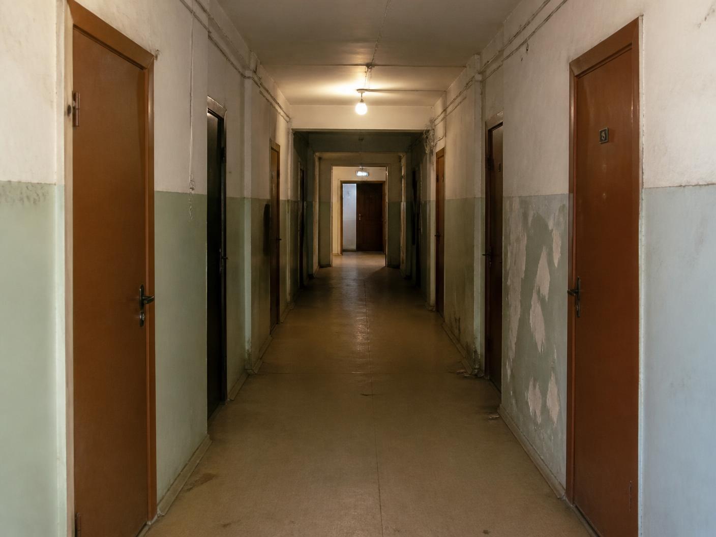 Korytarz przed remontem — zniszczone ściany i stare drzwi